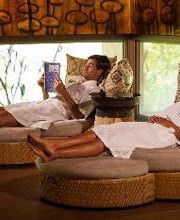 Personas descansando en sillones circulares, una leyendo y otra relajándose, en un entorno tranquilo.