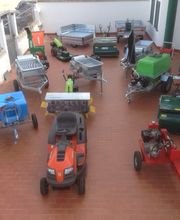 Macchinari agricoli su pavimento in cotto all'aperto, tra cui un trattorino arancione in primo piano.