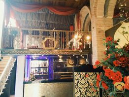 Ambiente interno de restaurante com decoração luxuosa, flores vermelhas e balcão ornamentado.