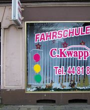 Fahrschule C. Kwapp mit Telefonnummer auf Schaufenster und Ampelsymbolen an einer Straßenfront.
