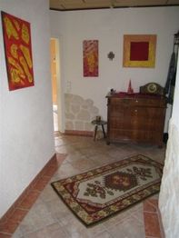 Flur mit Wandkunst, antiker Kommode und einem Teppich auf Fliesenboden.