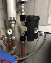 Rohrleitungen und Messgeräte in einem Heizungsraum mit Magnetfilter und Manometer.