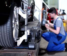 Automechaniker arbeitet an einem Auto, das auf einer Hebebühne steht.