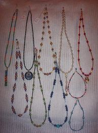Verschiedene bunte Halsketten hängen vor einem hellen Hintergrund.