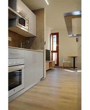 Cocina moderna y luminosa con electrodomésticos blancos y suelo de madera clara.