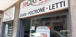 Facciata di un negozio di arredamento "Morfeo" con insegne per divani, poltrone e letti.