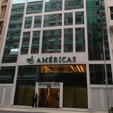 Fachada de um edifício moderno com o nome "Américas" na entrada.