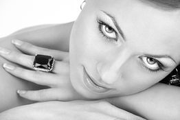 Frau mit großem Ring auf der Hand, die in die Kamera schaut. Schwarz-Weiß-Foto.