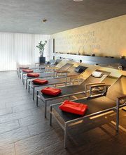 Entspannungsraum mit Liegestühlen, Kerzen und Obstkorb auf Steinboden.