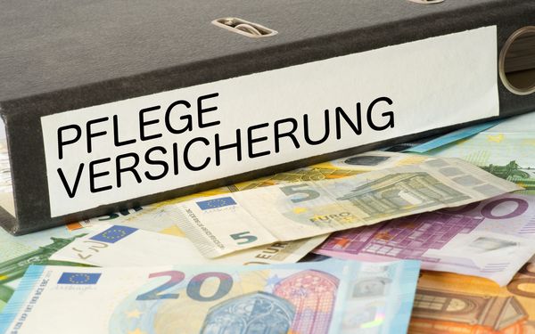 Ordner mit der Aufschrift Pflegeversicherung auf Geld