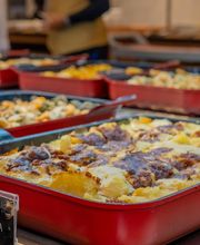 Buffet de lasanha vegetariana e outros pratos em bandejas vermelhas.