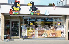 Kinderbuchladen mit Raben-Dekor, Fenster zeigt Bücher und Spielzeug.