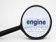 Magnifying glass enlarges the word "engine" over a background of binary code.