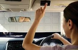 Person in car pressing a button, opening a garage door in front of them.