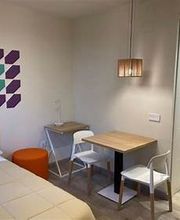 Habitación moderna con cama, mesa y sillas. Decoración geométrica en la pared.