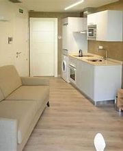 Sala moderna con sofá beige, cocina compacta y televisor en mueble marrón. Decoración geométrica.