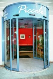 Blaue Drehtür des Restaurants Piccolo mit Einblick in den roten Eingangsbereich.