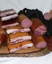 Eine Auswahl an verschiedenen Räucher- und Wurstwaren auf einem Holzbrett.