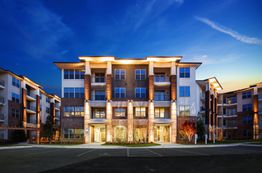 Modern apartment building illuminated at night against a twilight sky.