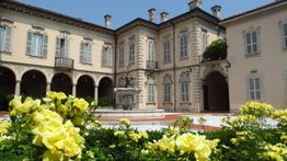 Palazzo storico con giardino fiorito e fontana al centro del cortile.