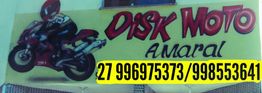 Placa amarela com desenho de moto, texto "Disk Moto Amaral" e dois números de telefone.