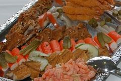 Platte mit Fisch, Krabben, Gurken und Gemüsesticks, appetitlich angerichtet.