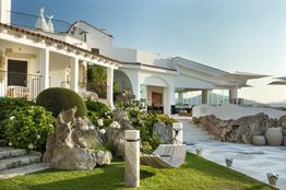 Villa elegante con giardino curato, amaca e vista sul mare in lontananza.