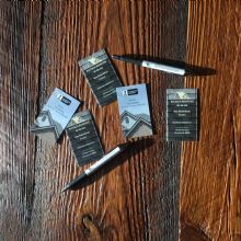 Business cards and pens arranged on a wooden table.