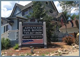 A blue house with a sign for Advanced Bail Bonds and an American flag design.