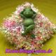 Grüne Froschfigur mit Krone auf rosa-blumigem Kissen, Schriftzug "KleineDingeLaden.de".