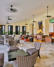 Sala moderna con sillas y mesas, decoración elegante, ventiladores en el techo y pantallas.