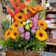 Vibrant floral arrangement with orange gerberas, pink roses, and spiky red blooms in a vase.
