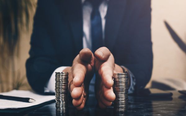 Ein Mann im Anzug, der zwei Münzstapel mit seinen Händen mittig trennt 