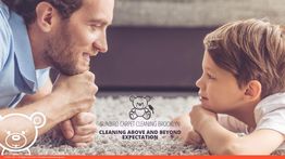 Father and child smiling at each other on a clean carpet. Company logo and text overlay.