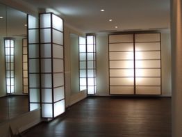Minimalistischer Raum mit beleuchteten Shoji Wänden, dunklem Boden und Spiegeln an der Wand.
