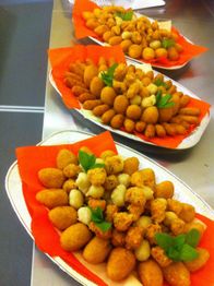 Vassoi di fritti assortiti su tovaglioli arancioni decorati con foglie di menta.