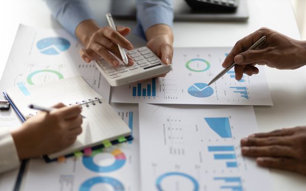 Drei Unternehmensberater analysieren den Jahresabschluss eines mittelständischen Unternehmens.