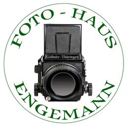 Schwarz-Weiß-Kamera im Kreis, umgeben von grünem Text: "Foto-Haus Engemann, Gößnitz/Thüringen".