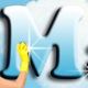 Hand mit gelbem Handschuh putzt einen glänzenden blauen Buchstaben "M" vor blauem Hintergrund.