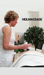 Frau bei einer Heilmassage, die neben einem Computer und Pflanze steht.