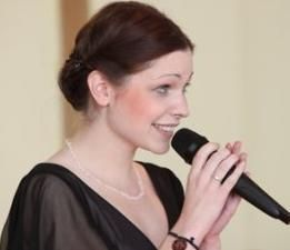 Frau hält ein Mikrofon und singt oder spricht freudig.