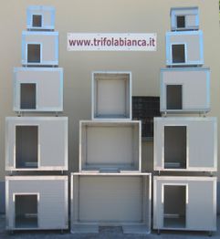 Gabbie metalliche impilate con insegna "www.trifolabianca.it" su parete gialla.