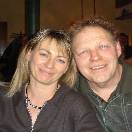 Ein lächelndes Paar sitzt zusammen in einem gemütlichen Raum.