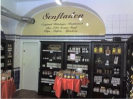 Regale mit verschiedenen Senf-Gläsern in einem Laden, Schild über der Auswahl an der Wand.