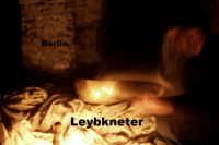 Ein verschwommenes Bild einer Person, die in schwachem Licht Teig knetet. Text: "Leybknetter".