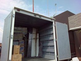 Camión de mudanza abierto, con cajas y muebles en su interior. Día soleado.