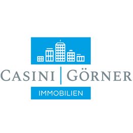 Logo von Casini Görner Immobilien mit blauen Gebäudesymbolen und Schriftzug in Grau.