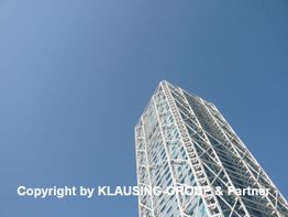 Diagonalaufnahme eines modernen Gebäudes mit Gitterstruktur vor klarem, blauem Himmel.