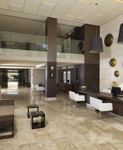 Vestíbulo moderno con muebles de madera y luces colgantes negras en un piso de mármol.