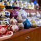 Colorful ceramic teapots of various designs displayed on a wooden shelf in a shop.